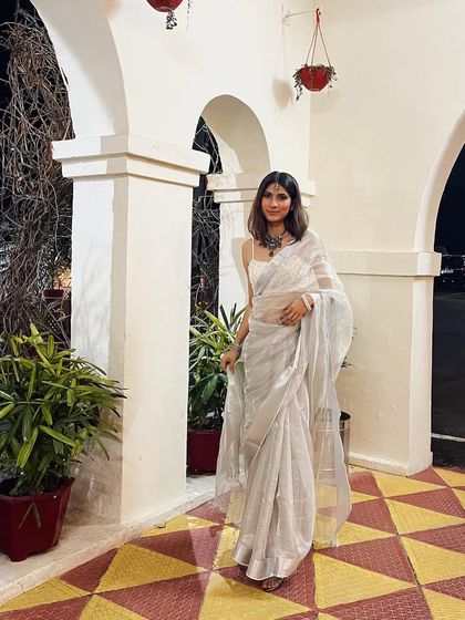 A full-length shot of the white sari, showing its graceful drape and subtle shimmer. It's a look of pure elegance.