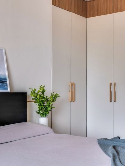 The corner wardrobe in this guest room makes smart use of space, providing ample storage without feeling bulky. The two-tone design with custom wooden handles keeps it light and modern.