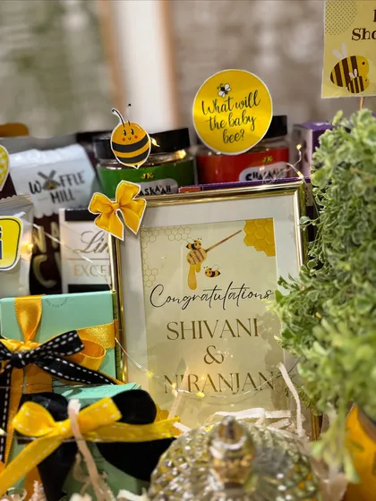 A personalized frame congratulating the parents-to-be, Shivani and Niranjan, sits amongst jars of treats and beautifully wrapped gifts.