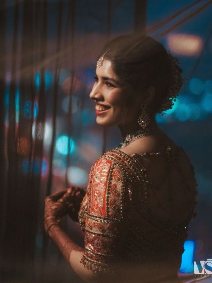 A candid shot of Vedika smiling, with the city lights creating a beautiful bokeh effect in the background. This portrait feels modern, happy, and full of life.