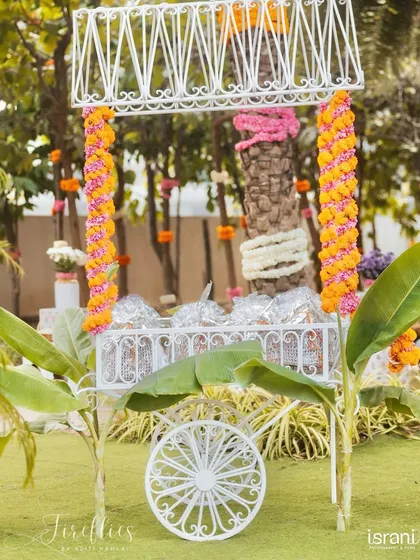 A traditional drink cart decorated with marigold garlands, ready to serve guests at the outdoor celebration.