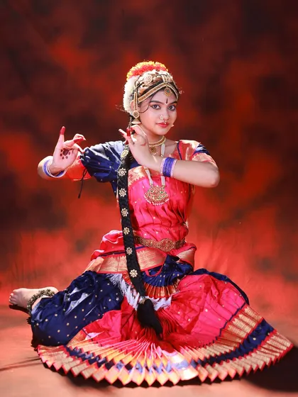 Here, the focus is on the hand gestures, or mudras, central to classical dance. The seated pose allows the pleated saree to fan out beautifully, showcasing the costume's design.