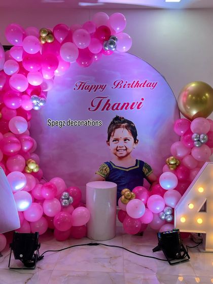A personalized birthday backdrop featuring a photo of the birthday girl, Thanvi, surrounded by a vibrant pink balloon arch for her 4th birthday.