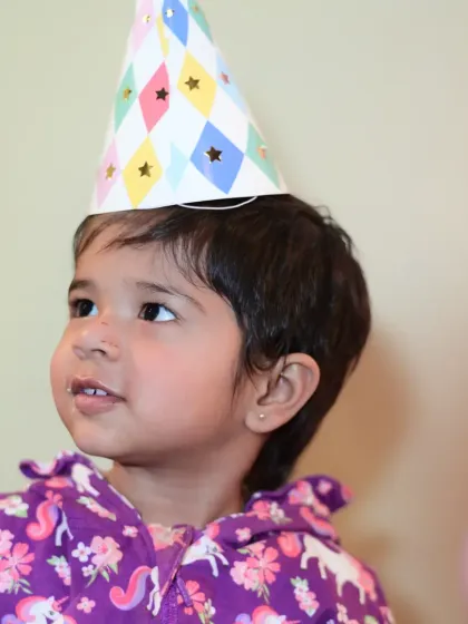A little guest in a party hat, looking up with wonder. Capturing the magic of childhood is what I do best.