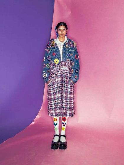 A clean, minimalist hairstyle for a péro brand photoshoot. The hair is pulled back neatly with a side part, creating a simple and strong look that contrasts with the detailed, embroidered denim jacket.