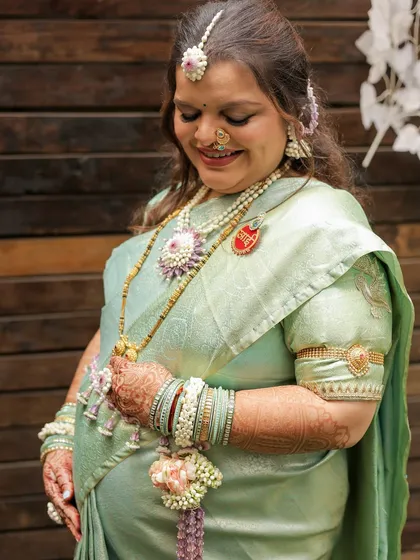 This photo shows the full baby shower look, including the necklace, bajuband, and haath phool. The jewellery is designed to complement her intricate henna.