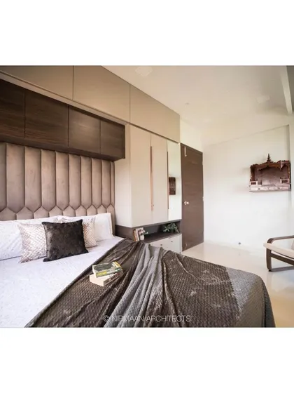 A cozy parent's bedroom with a floor-to-ceiling upholstered headboard. This design feature not only adds comfort but also makes the room feel taller and more spacious.