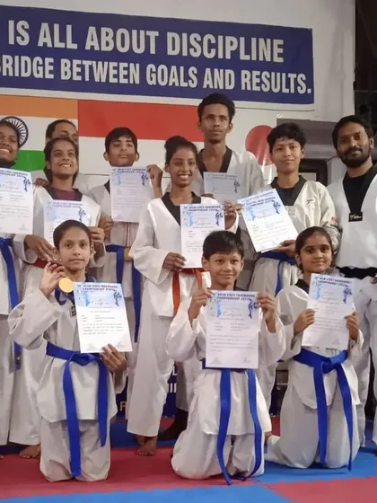 Students holding up their certificates and new uniforms, rewards for their success in state-level competitions and belt tests.
