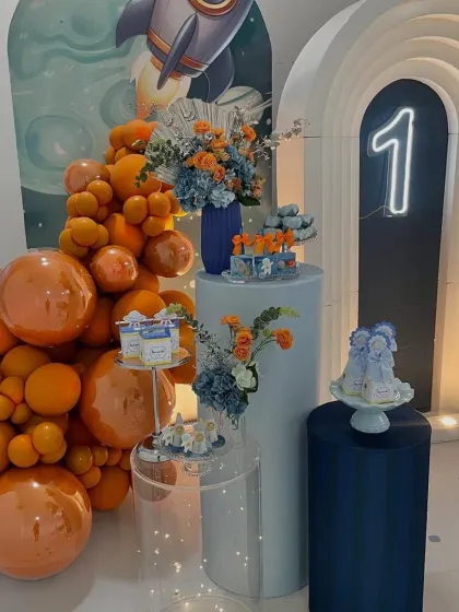 The dessert station for our space party, featuring themed treats, beautiful floral arrangements, and a bold orange balloon garland.