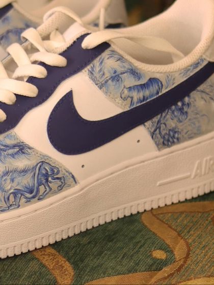A side view of the Dior-inspired custom sneakers. The deep blue paint stands out beautifully against the crisp white leather of the Air Force 1s.