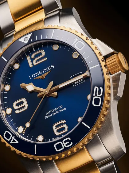 A detailed macro shot of the Longines HydroConquest. The challenge here was to capture the deep, sunray blue of the dial and the brushed texture of the steel bezel while keeping the gold accents rich and vibrant.