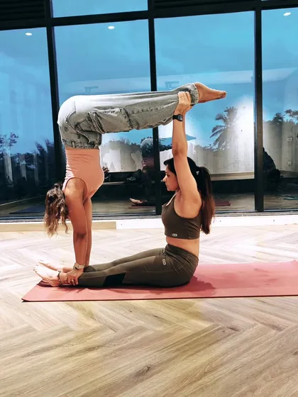 Acro Yoga is all about creating shapes and building trust. Here, my partner acts as a stable base while I practice an L-sit handstand, a pose that requires immense core strength and communication between us.