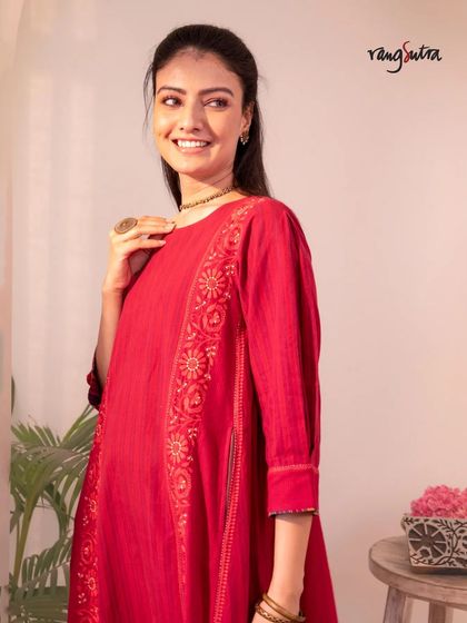 A smiling model in our red Haveli kurta. The piece is crafted from pure handwoven cotton and adorned with hand-embroidered Chikankari motifs, perfect for your celebrations.