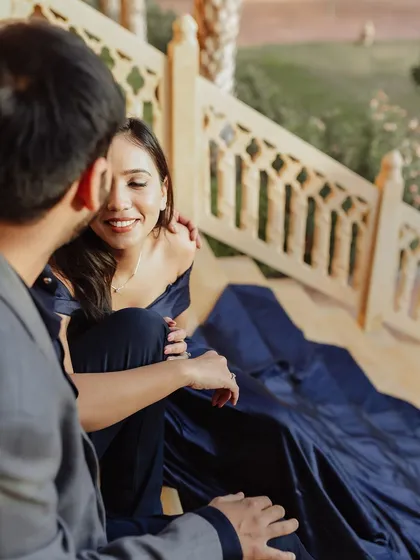 An intimate and tender moment on the steps of a palace. The groom's loving gaze and the bride's gentle smile speak volumes, capturing the deep affection and connection between them in a beautiful, candid way.
