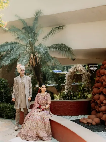 A posed portrait of the couple in the wedding venue, showcasing their coordinated pastel outfits and the beautiful, earthy decor.