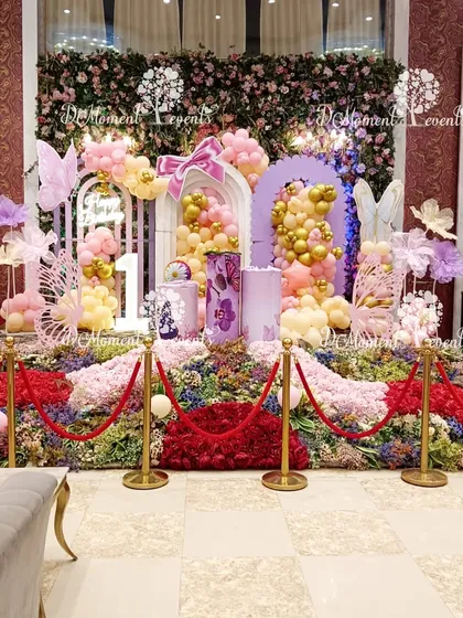 A wide view of the enchanting butterfly-themed first birthday decoration. This shot showcases the entire stage setup against a rich, patterned wallpaper, highlighting the scale and detail of the decor.