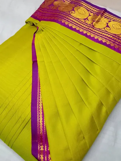 A parrot green and purple silk saree, pleated and ready to wear.