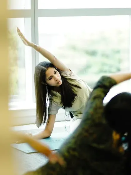 Here I am guiding participants through a side stretch during a university wellness event. My approach is hands-on and supportive, ensuring everyone can participate safely and effectively, regardless of their experience level. I focus on proper alignment to maximize benefits and prevent injury.