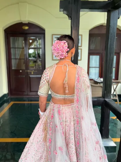 The full back view of the bride's outfit and hairstyle. The large floral bun makes a beautiful statement against the intricate embroidery of her blouse.
