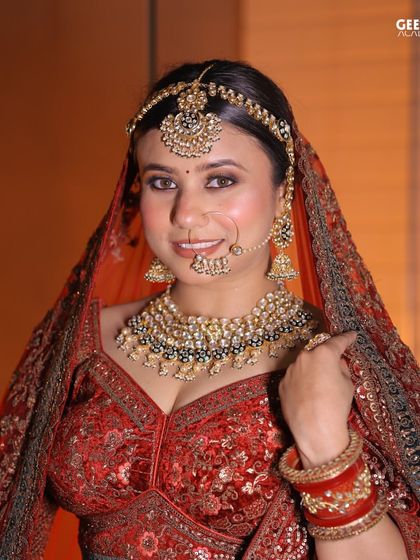 Student Work: A happy bride on her special day. This look, created by one of our students, features a classic red lehenga with beautifully coordinated makeup, including a bold red bindi.