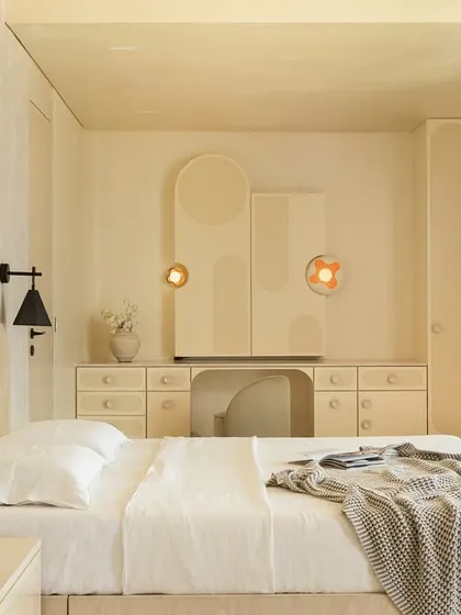 The master suite in the 'Soft Serve' project is enveloped in a timeless taupe. The custom bed and vanity feature abstract patterns in Movingue White veneer, with scalloped motifs framing the bay window.