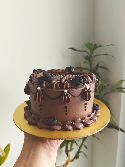 The same vintage chocolate cake from another angle, showing the intricate swag and shell piping details around the sides.