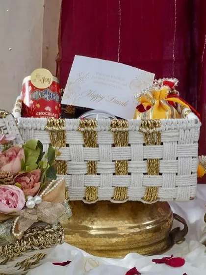 A closer look at the elegant white and gold woven basket from our Rang & Noor collection. It’s filled with chocolates, festive potlis, and a personalized Diwali card, ready to delight.