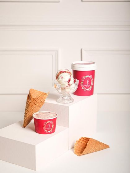 Our strawberry swirl ice cream, shown in a tub, a cup, and with cones. Enjoy our handcrafted ice cream any way you like.
