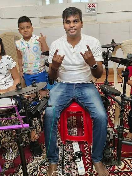 A coach with his young drum students. Using electronic drum kits allows for quiet practice and exploration of different sounds, making it perfect for our group lessons.