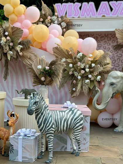 A zebra and elephant prop stand amongst beautifully wrapped gifts that match the pastel jungle theme.