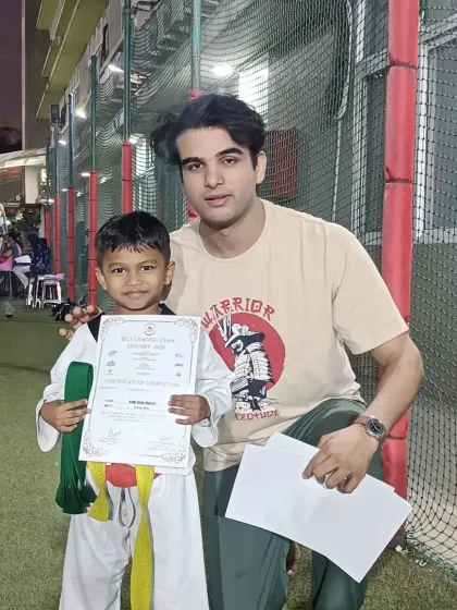 A proud moment for this young student, certificate in hand after his successful grading.