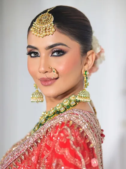 A beautiful side profile showcasing the elegant floral bun and the flawless finish of the makeup. The nude lip balances the strong eye makeup perfectly.
