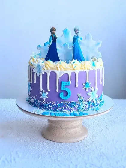 A full view of the purple Frozen drip cake on its stand.