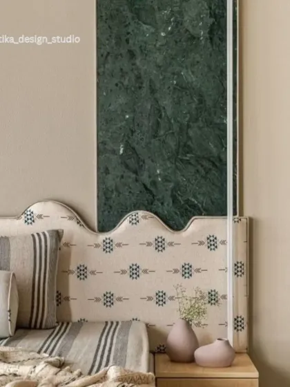 This is a close-up of a bespoke headboard and wall treatment where I combined different materials to create a unique focal point. The design features a panel of bold green marble, a custom-upholstered headboard with a subtle pattern, and warm neutral tones for a look that is both artistic and serene.