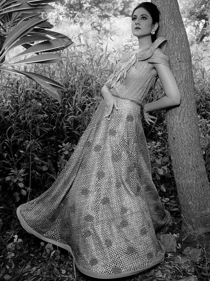 The same polka-dot gown, this time in a classic black and white. The monochrome treatment emphasizes the texture of the fabric and the model's elegant pose against the tree.