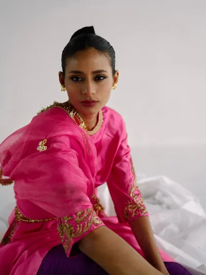 A striking portrait for Eshaarora.in, with the model in a bright pink and gold embroidered outfit, looking directly at the camera.
