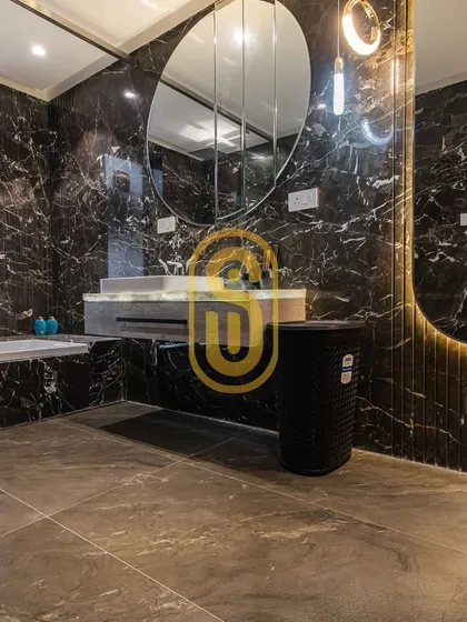 A glimpse into a bathroom designed for ultimate relaxation. We used dramatic black marble for the walls and a large, modern mirror to create a spa-like experience, handling all tiling and fixture installation.