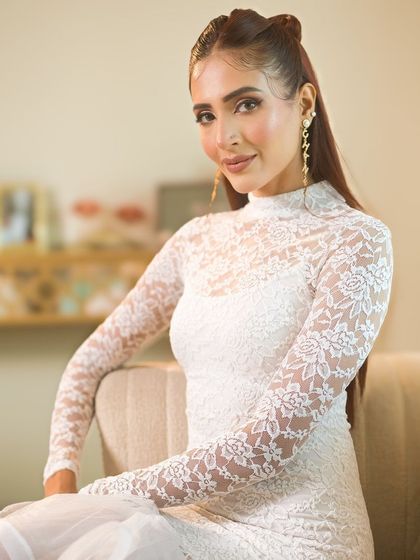 A high-fashion look with a soft, peachy glam makeup. The client is wearing a beautiful white lace dress, her makeup enhancing her delicate features.
