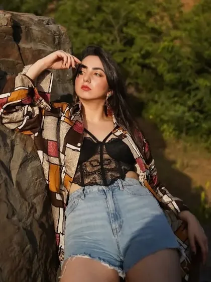 An outdoor shoot featuring a black lace bralette, denim shorts, and a printed shirt. This is a bold and stylish summer look.