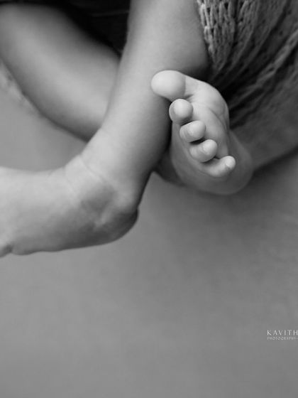 A black and white macro shot of a newborn's tiny, crossed feet. These are the little things you'll never want to forget.