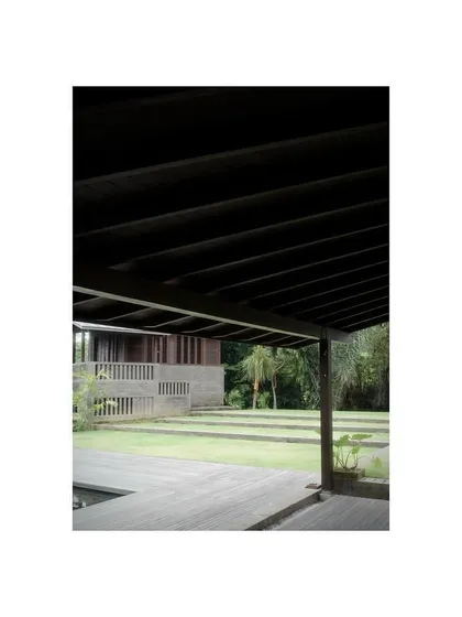 A view from a veranda in our Bali project, looking out over the lawn and timber pavilions. The design uses dark, rich wood to create a sense of calm and connection to the surrounding jungle.