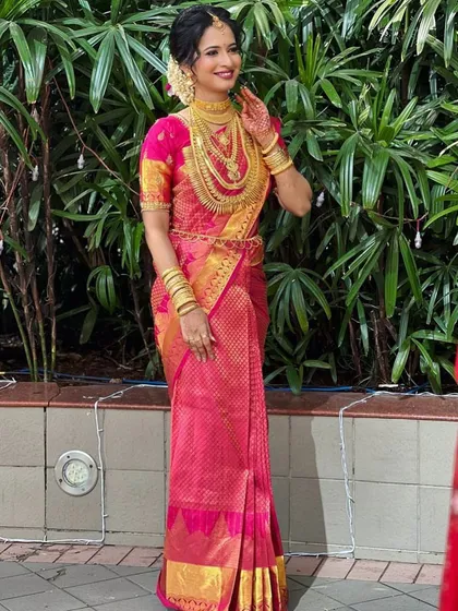 This bride is a vision in pink. Her vibrant Kanjivaram saree and extensive gold jewellery create a look of pure bridal magnificence.