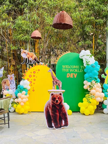 Welcome to the wild! This jungle-themed decoration for a "Welcome to the World" party features a variety of animal cutouts like a bear, tiger, and zebra, set against a custom green and yellow backdrop with balloon accents.