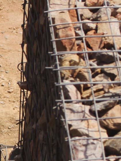 A detail of the gabion wall construction at the Aravali Amphitheatre. This technique uses a simple steel mesh filled with loose rock and stone from the site, creating a strong, porous, and ecologically sensitive retaining wall.