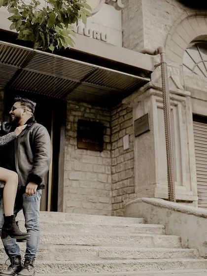 A romantic moment on a city street, with the bride touching the groom's face, set against a classic stone building.