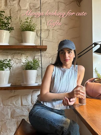 A casual cafe look. I paired a blue knit tank top with jeans and a baseball cap for a relaxed and comfortable vibe.