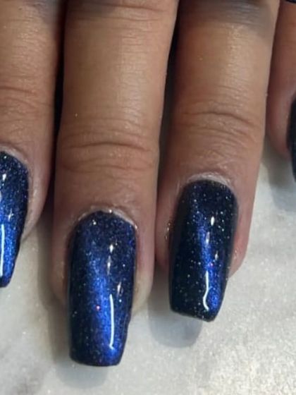 A deep, galaxy-inspired cat-eye manicure. This dark blue magnetic polish is full of fine glitter, creating the look of a starry night sky on your nails.