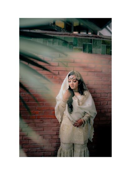 A full-length portrait of Lubna against a brick wall, her serene expression and graceful pose captured beautifully.