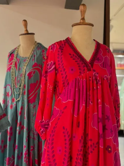 The vibrant pink and red printed kaftan stands out in this display, offering a bold and cheerful option for a summer day.