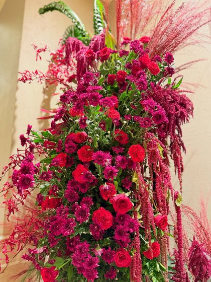 The dense layering of different red blooms, from chrysanthemums to roses, creates a rich and velvety texture that is visually captivating.